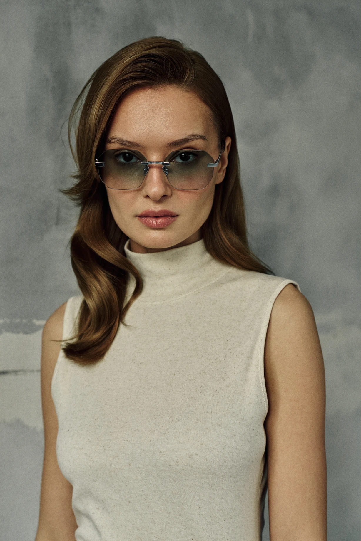 Woman in a cream turtleneck wearing IRIS Jade silver hexagonal sunglasses with green gradient lenses
