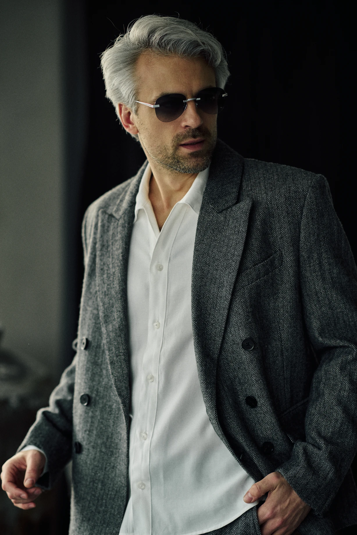 Man in a grey herringbone double-breasted jacket wearing PTERON Charcoal silver aviator sunglasses