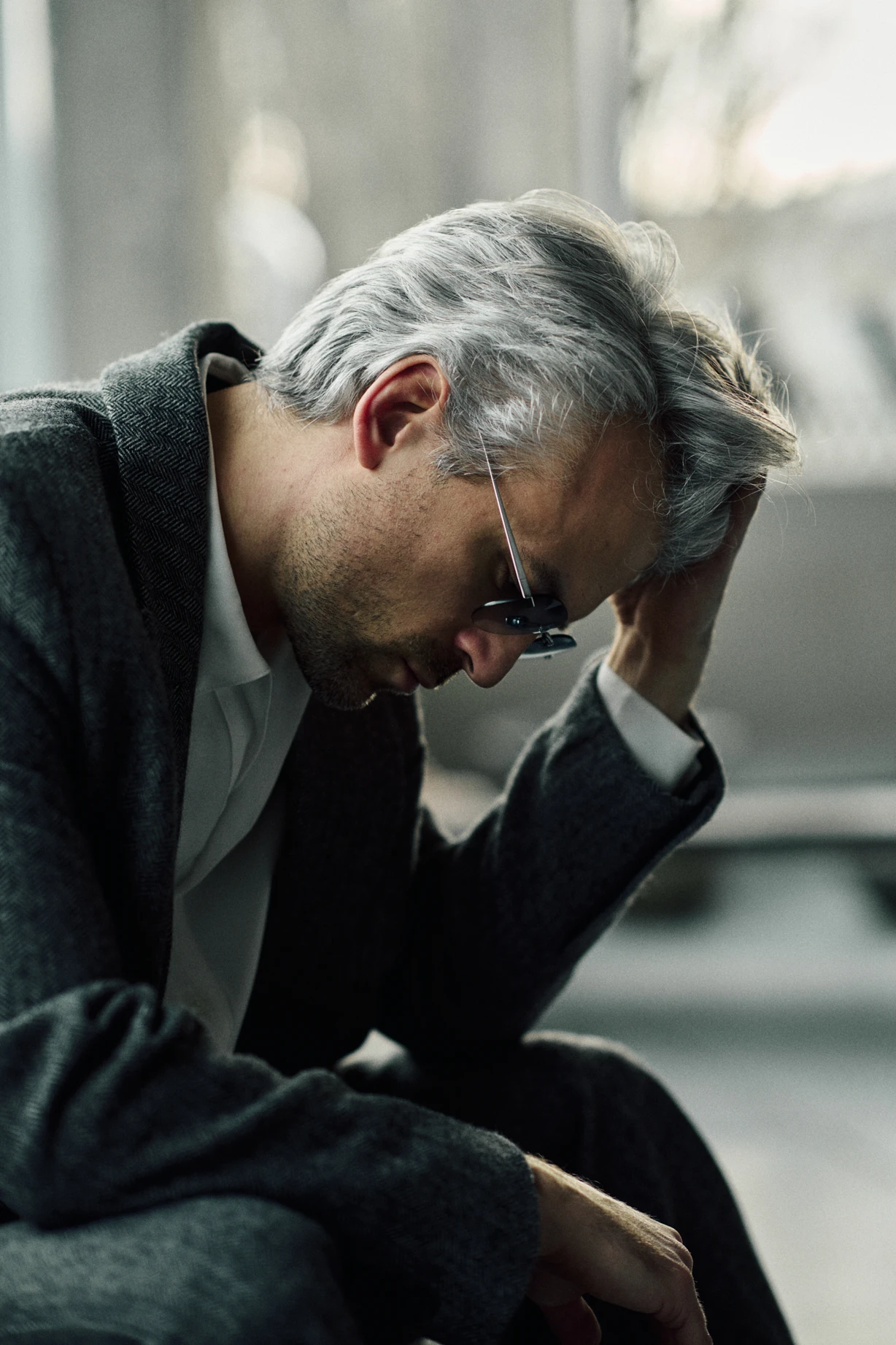 Man with his head lowered, wearing PTERON Azure silver rimless aviator sunglasses