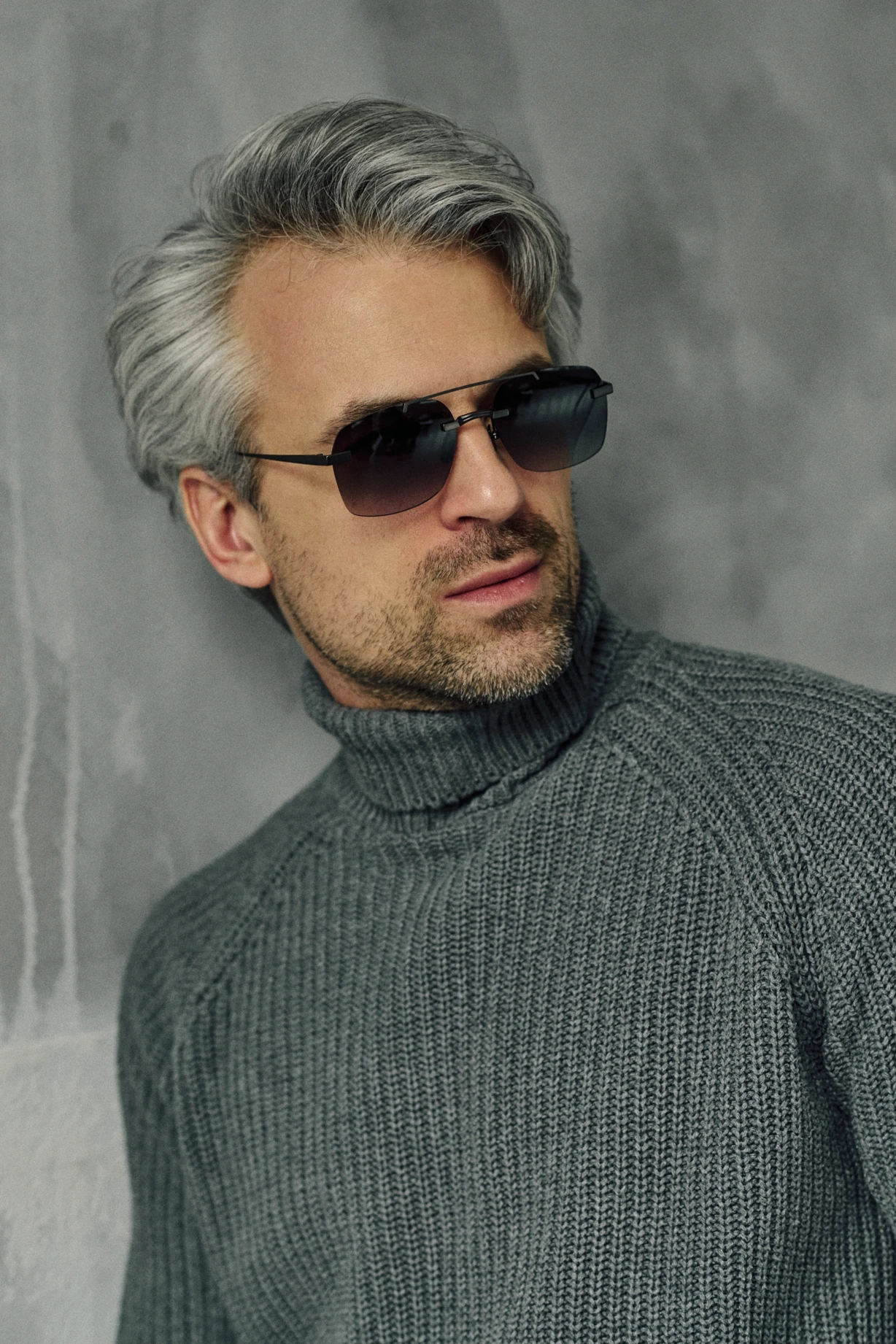 Man in a grey knit turtleneck wearing NOUS Obsidian black double-bridge sunglasses